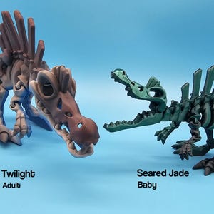 Pu&ograve; includere: Due scheletri di dinosauro di plastica, uno adulto e uno bambino. L'adulto &egrave; di colore marrone e blu ed &egrave; etichettato "Twilight Adult". Il bambino &egrave; verde ed &egrave; etichettato "Seared Jade Baby".
