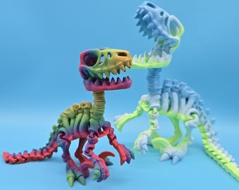 May include: Two articulated dinosaur skeletons, one in a rainbow color scheme and the other in a light blue and green color scheme.