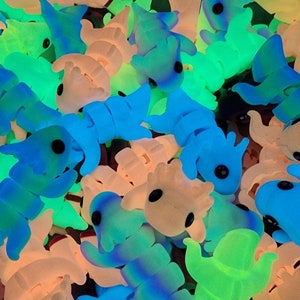 May include: A collection of small, colourful, glow-in-the-dark toys shaped like various creatures. The toys are made of a soft, rubbery material and have large, black eyes.