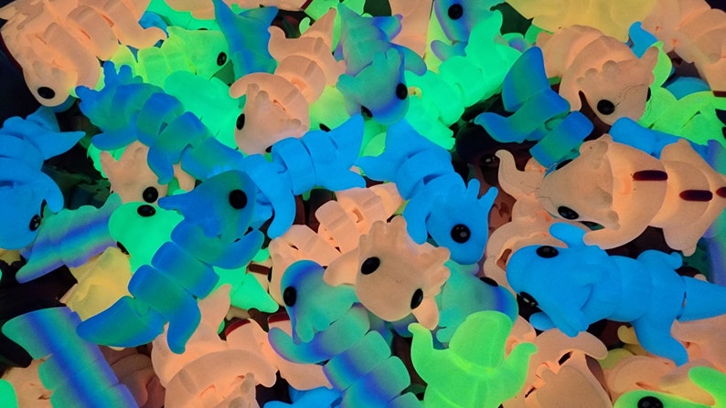 May include: A collection of small, colourful, glow-in-the-dark toys shaped like various creatures. The toys are made of a soft, rubbery material and have large, black eyes.