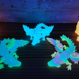May include: Five glow-in-the-dark dragon figurines in various shades of green, blue, and yellow. The dragons are posed in flight with wings outstretched.