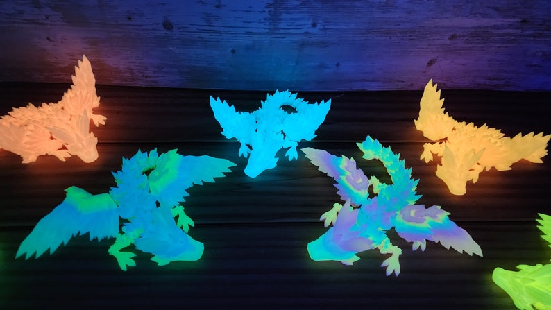 May include: Five glow-in-the-dark dragon figurines in various shades of green, blue, and yellow. The dragons are posed in flight with wings outstretched.