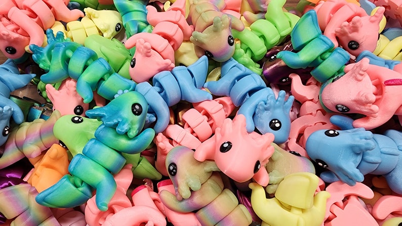 May include: A collection of colourful, bendable, plastic toys shaped like dragons. The toys are in various shades of blue, green, pink, yellow, and purple.