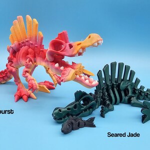 Pu&ograve; includere: Due scheletri di dinosauro articolati, uno in uno schema di colori arancione e rosa vibrante etichettato "Sunburst" e l'altro in uno schema di colori verde scuro etichettato "Seared Jade".