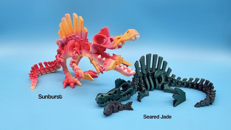 Pu&ograve; includere: Due scheletri di dinosauro articolati, uno in uno schema di colori arancione e rosa vibrante etichettato "Sunburst" e l'altro in uno schema di colori verde scuro etichettato "Seared Jade".