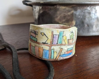 Clay bangle bracelet featuring a hand painted bookcase scene, wearable whimsical clay art