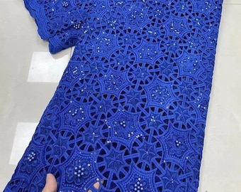 May include: Royal blue lace fabric with a delicate, intricate pattern and small, round embellishments. The fabric has a cut-out design, creating a see-through effect.