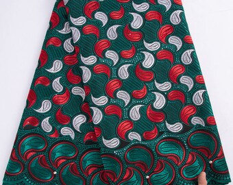 May include: Green, red, and white lace fabric with a paisley pattern. The fabric has a scalloped edge.
