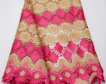May include: Pink and gold lace fabric with a floral pattern. The lace has a scalloped edge.