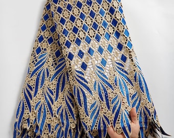 Könnte beinhalten: Blaue und goldene Spitzenstoff mit einem Rautenmuster und einem Blumendesign. Die Spitze ist zart und filigran und eignet sich perfekt für eine Vielzahl von Projekten, wie z. B. Kleidung, Accessoires und Dekoration.