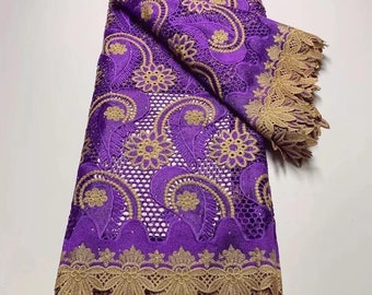 May include: Purple and gold lace fabric with a paisley pattern. The lace has a scalloped edge.