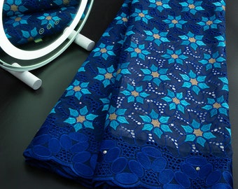 May include: Blue and turquoise lace fabric with a floral pattern. The lace has a scalloped edge.