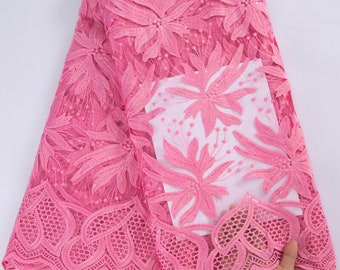 May include: Pink floral lace fabric with a delicate pattern and sequins. The lace has a scalloped edge.