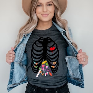 May include: A dark grey heather t-shirt with a black skeleton ribcage design filled with colorful candy. The text "Dark Grey Heather" is visible at the bottom of the image.