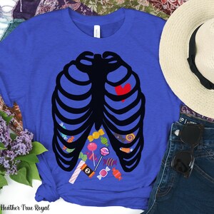 May include: A royal blue t-shirt with a black skeleton outline filled with colorful candy. The skeleton has a red heart in the center of its chest.