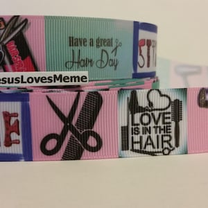May include: A decorative ribbon featuring a repeating pattern of hairstyling tools and phrases. The design includes scissors, combs, and text that reads "Have a great Hair Day" and "Love is in the Hair". The color scheme includes pink, teal, and purple.