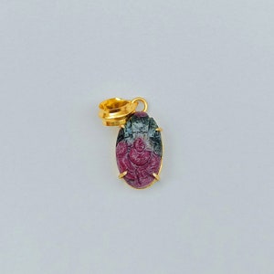 Peut inclure: Un pendentif en or avec une pierre précieuse verte et rose sculptée. La pierre précieuse est de forme ovale et présente une sculpture détaillée.