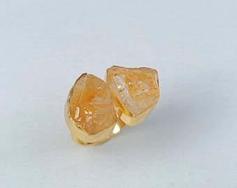 May include: A gold ring with two raw, clear, and yellow citrine stones.