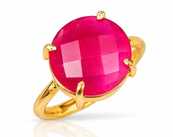 Könnte beinhalten: Ein Goldring mit einem großen, runden, facettierten, pinkfarbenen Edelstein in einer Vier-Krappen-Fassung. Die Ringschiene ist aus glattem, poliertem Gold gefertigt und bildet einen hellen Kontrast zu der leuchtenden, satten Pinkfarbe des Steins.