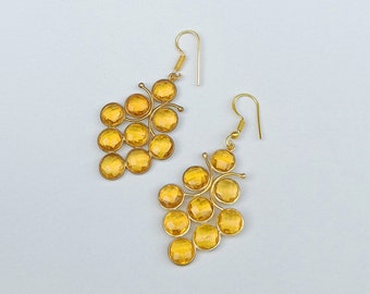 May include: A pair of gold earrings with a cluster of amber-colored glass beads shaped like grapes.