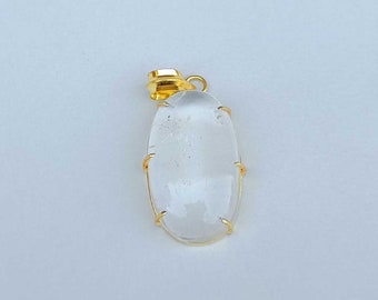以下が含まれることがあります： 金色の枠にセットされた透明な水晶のペンダント。ペンダントは楕円形で、滑らかで磨かれた仕上げです。