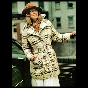 May include: A woman wearing a brown hat and a white and brown plaid belted coat. The coat has a collar and pockets.