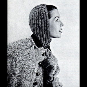 May include: Black and white photograph of a woman wearing a knitted hood and a tweed jacket with black buttons. The hood covers the head and neck, and the jacket has a collar and long sleeves. The woman is wearing black gloves.