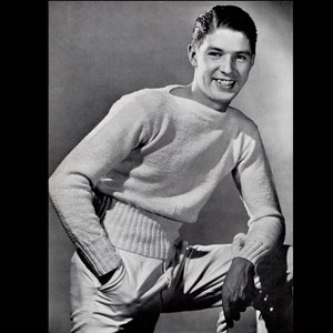May include: A black and white photograph of a person wearing a cream-colored sweater and light-colored pants. The sweater has a ribbed hem and cuffs. The person is smiling and leaning against a surface with one hand in their pocket.