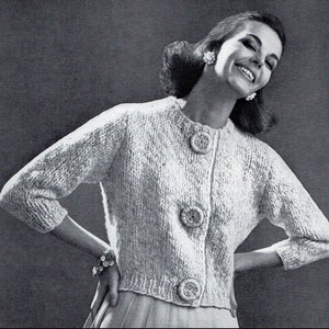 Puede incluir: Un cárdigan de punto blanco con cuello redondo y tres botones grandes en la parte delantera.