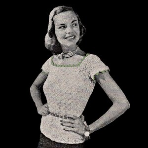 May include: A white crocheted top with a green trim around the neckline and sleeves. The top has a fitted silhouette and short sleeves.