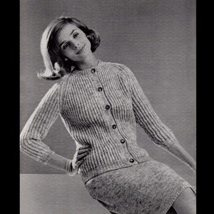 Puede incluir: Un cárdigan de punto gris con cierre de botones y mangas largas. El cárdigan está hecho de un hilo suave y texturizado.