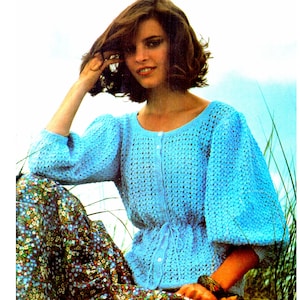 May include: A light blue crocheted cardigan with a round neckline and button closure. The cardigan has a fitted waist and puffed sleeves.