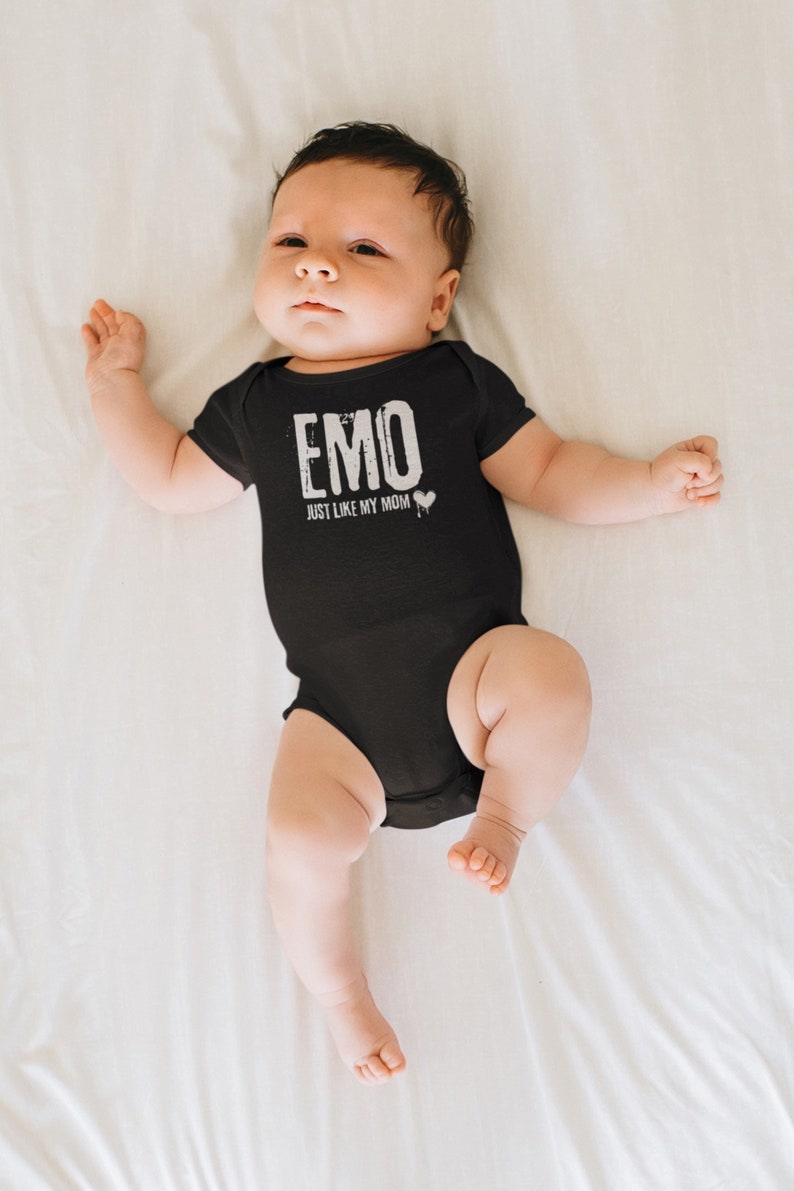 Pu&ograve; includere: Un body per neonato nero con testo bianco che recita "EMO JUST LIKE MY MOM" con un cuore bianco.