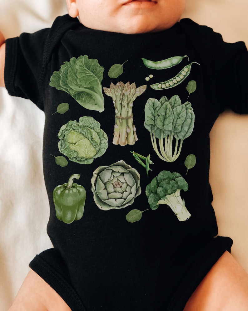 May include: A black baby onesie with a green and white print of various vegetables, including asparagus, broccoli, artichoke, cabbage, spinach, and peppers.