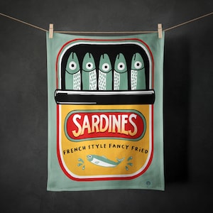May include: A teal kitchen towel featuring a sardine can illustration. The can is yellow with red text that reads "Sardines" and "French Style Fancy Fried". The top of the can is black, and it contains five green fish.