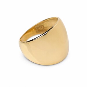May include: A polished gold ring with a wide, smooth, and domed band. The ring features a high-shine, reflective surface that curves outward, creating a solid and continuous circular shape. The interior of the band is visible, showing a smooth finish.