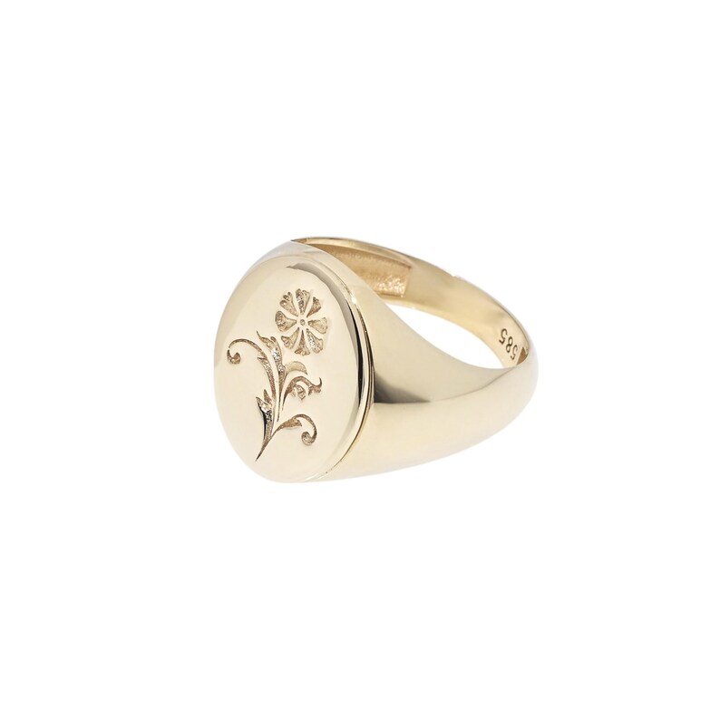 May include: A gold signet ring featuring an oval face with an engraved floral motif. The interior of the band is clearly stamped with the number 585, indicating the gold purity. The ring has a polished, smooth finish and a tapered band design.