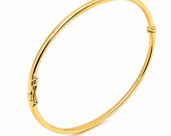 May include: A polished yellow gold bangle bracelet with a smooth, rounded surface. The circular piece features a secure hinged clasp mechanism on one side and a small, integrated hinge joint on the opposite side, creating a continuous loop design.