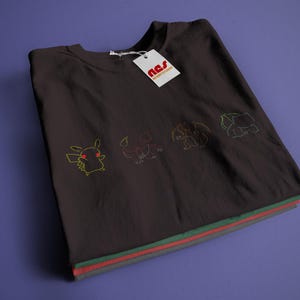 May include: A black t-shirt featuring a graphic of Pokemon characters, including Pikachu, Charmander, Bulbasaur, and Squirtle. The shirt has a white tag with the text "n.s.s. streetwear" on it.