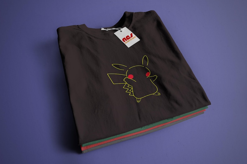 May include: A black t-shirt featuring a yellow outline of Pikachu with red eyes. The t-shirt is folded and has a white tag with the text "nss" on it.