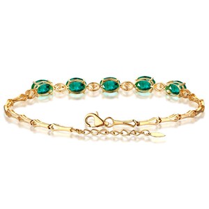 May include: A gold bracelet with a chain link design and oval-shaped green gemstones.