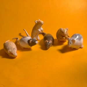 May include: A collection of ceramic mouse figurines in various poses and colors, including white, brown, and gray. The mice are set against a bright yellow background, creating a playful and whimsical scene. These decorative figurines are ideal for collectors.