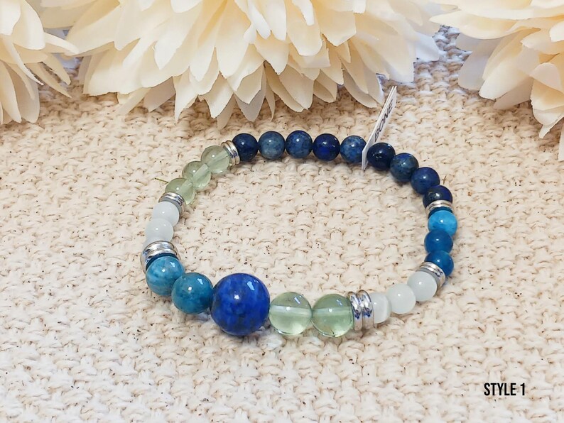 Pode incluir: Um bracelete de contas azuis, verdes e brancas com espa&ccedil;adores prateados. O bracelete apresenta uma grande pedra preciosa azul no centro.