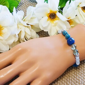 Pode incluir: Um bracelete com contas azuis, verdes e brancas sobre um fundo branco. O bracelete &eacute; feito de pedras naturais e &eacute; enfiado em uma corrente de prata.