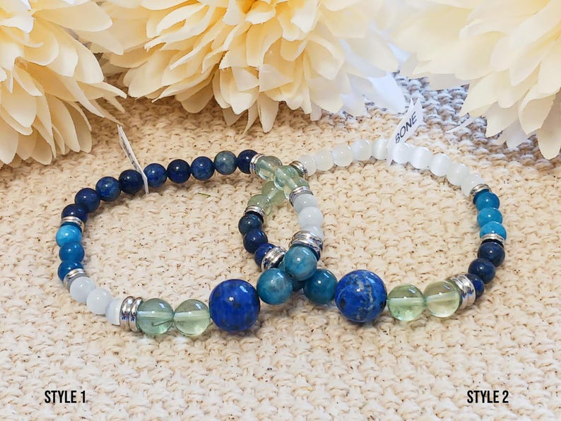 Pode incluir: Duas pulseiras de contas com pedras azuis, verdes e brancas. A pulseira da esquerda tem um fecho prateado e a pulseira da direita tem um fecho de pedra branca. As pulseiras s&atilde;o etiquetadas como "STYLE 1" e "STYLE 2".