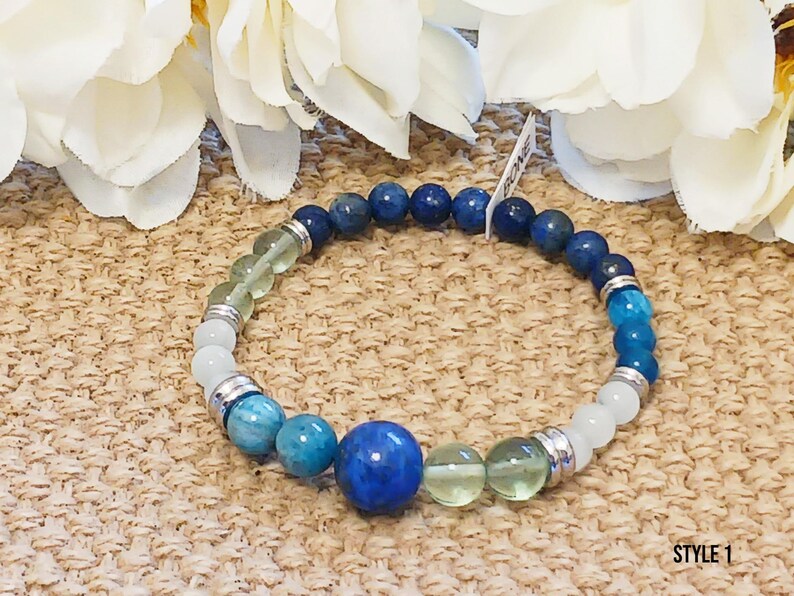 Pode incluir: Um bracelete de contas azuis, verdes e brancas com espa&ccedil;adores prateados. O bracelete tem uma grande pedra preciosa azul no centro.