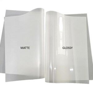 May include: Two sheets of clear printable transfer paper, one matte and one glossy. The matte sheet has a subtle texture, while the glossy sheet has a smooth, reflective surface.