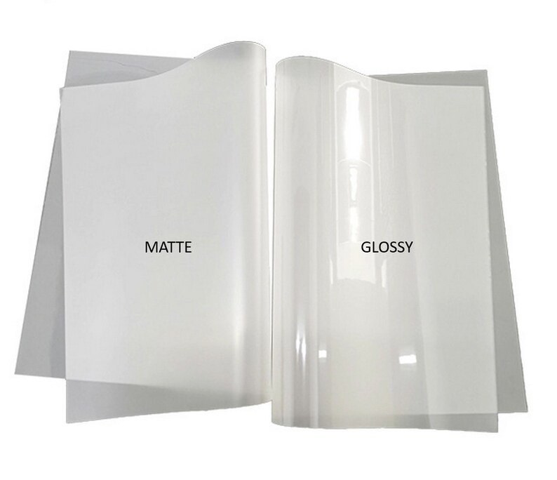 May include: Two sheets of clear printable transfer paper, one matte and one glossy. The matte sheet has a subtle texture, while the glossy sheet has a smooth, reflective surface.