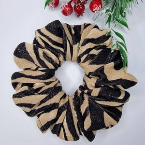 May include: A brown and black zebra print scrunchie with a sparkly finish.