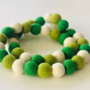 May include: A garland of white and green felt balls. The balls are strung together to create a decorative garland.